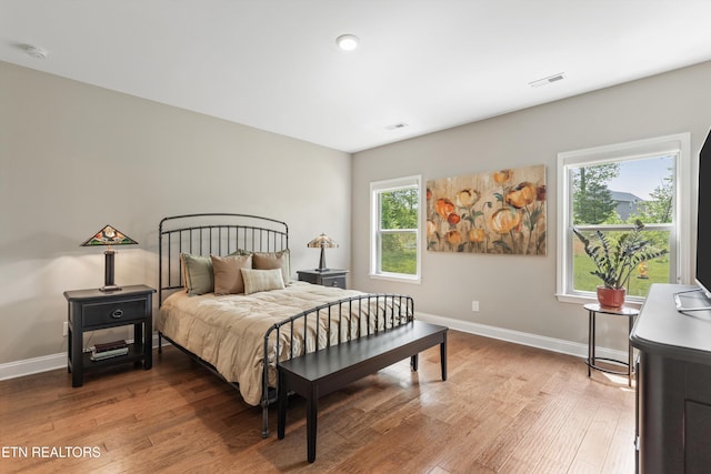 bedroom featuring baseboards, visible vents, and wood finished floors