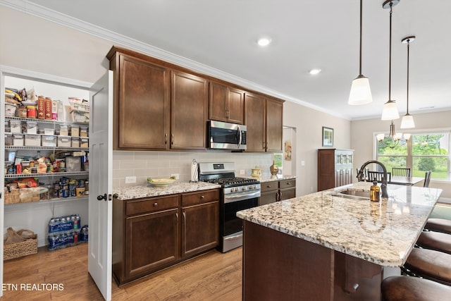 kitchen featuring light wood-style floors, stainless steel appliances, a breakfast bar area, and crown molding