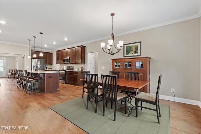 dining room featuring an inviting chandelier, light wood-style flooring, baseboards, ornamental molding, and recessed lighting