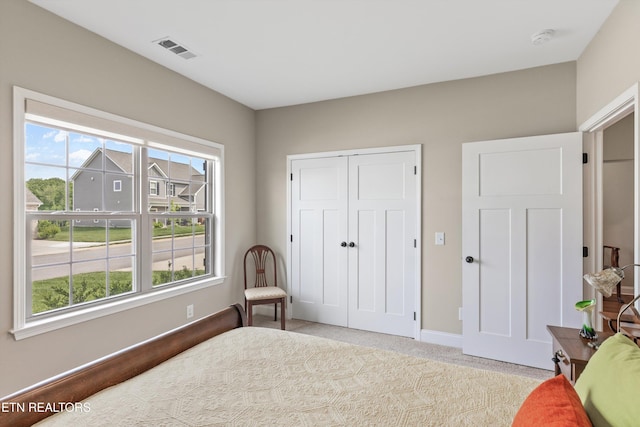 bedroom with light colored carpet, multiple windows, visible vents, and baseboards
