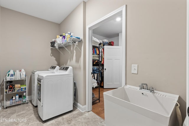 laundry area featuring baseboards, laundry area, a sink, and washer and clothes dryer