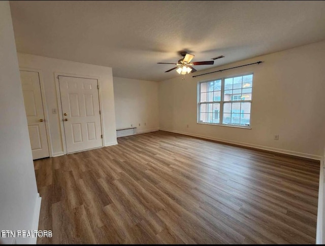 spare room featuring ceiling fan, visible vents, baseboard heating, wood finished floors, and baseboards