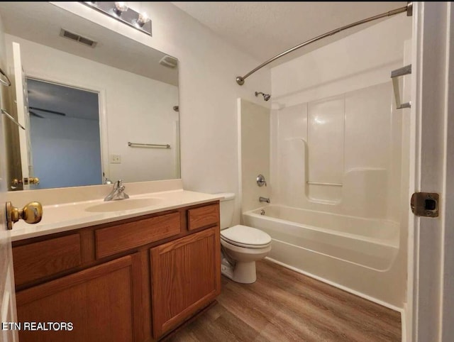bathroom with washtub / shower combination, vanity, toilet, wood finished floors, and visible vents