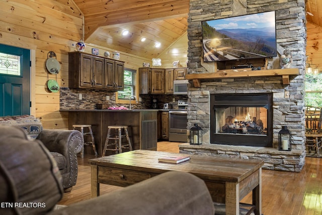 2471 Cove Mountain Ln, Sevierville, TN 37862 - living room with a stone fireplace, wooden walls, high vaulted ceiling, wooden ceiling, and light wood finished floors