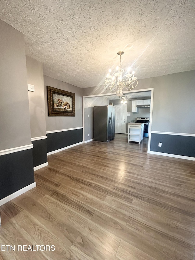 526 S Castle St, Knoxville, TN 37914 - unfurnished dining area with baseboards, a textured ceiling, a notable chandelier, and wood finished floors