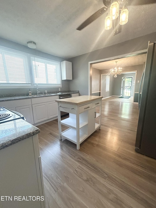526 S Castle St, Knoxville, TN 37914 - kitchen with a sink, ceiling fan with notable chandelier, freestanding refrigerator, white cabinetry, and wood finished floors