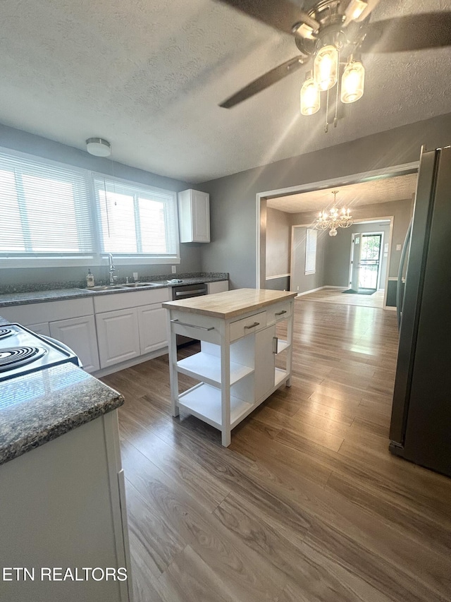 526 S Castle St, Knoxville, TN 37914 - kitchen with a textured ceiling, dark wood finished floors, white cabinets, freestanding refrigerator, and ceiling fan with notable chandelier