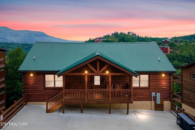 view of front of home featuring log exterior, a mountain view, and metal roof