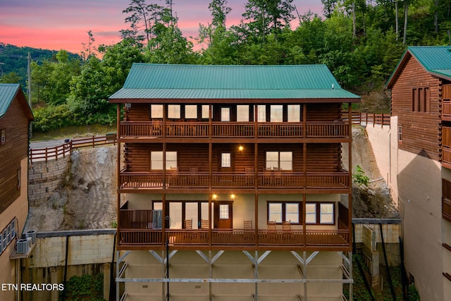 view of front of house featuring log siding, a balcony, and metal roof