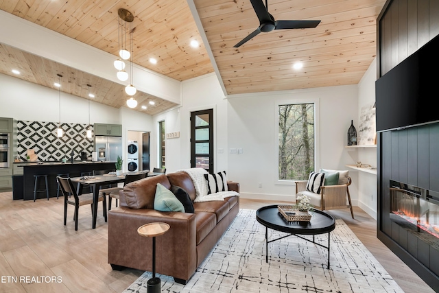 - Chinquapin Drive, Sevierville, TN 37876 - living room with stacked washer and dryer, a glass covered fireplace, wooden ceiling, light wood-style flooring, and vaulted ceiling