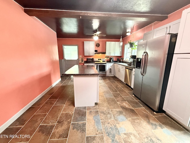 kitchen with a kitchen island, dark countertops, a sink, baseboards, and stainless steel appliances