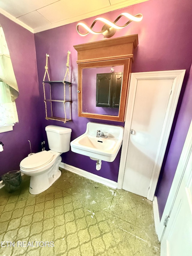 bathroom with crown molding, toilet, baseboards, and a sink