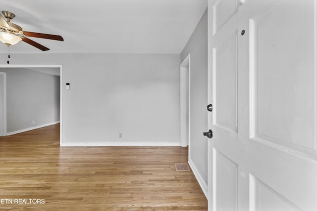 unfurnished room with baseboards, visible vents, light wood-style flooring, and ceiling fan
