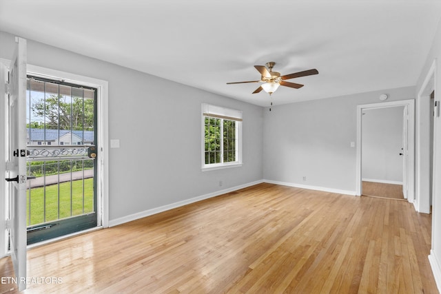 empty room featuring a ceiling fan, baseboards, and light wood-style flooring