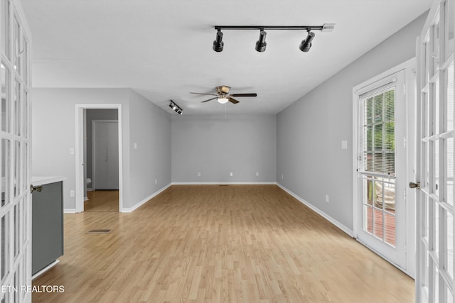 interior space featuring rail lighting, light wood-style flooring, baseboards, and a ceiling fan