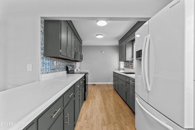 kitchen featuring backsplash, light wood-style floors, light countertops, and appliances with stainless steel finishes