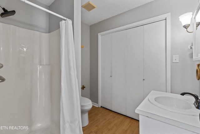 bathroom with toilet, wood finished floors, a shower with curtain, visible vents, and vanity