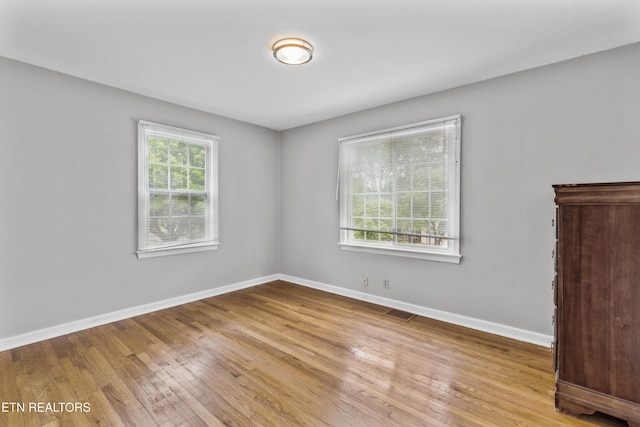spare room featuring baseboards, visible vents, and wood finished floors