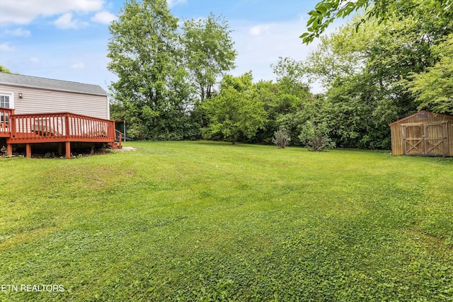 view of yard with an outdoor structure, a wooden deck, and a storage shed