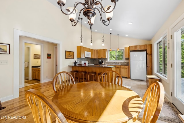 dining area with vaulted ceiling, light wood-type flooring, recessed lighting, baseboards, and a chandelier