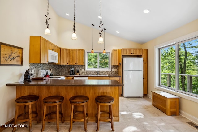 kitchen featuring white appliances, lofted ceiling, a peninsula, baseboards, and decorative backsplash