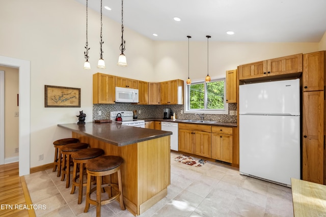 kitchen featuring white appliances, a sink, high vaulted ceiling, dark countertops, and a peninsula