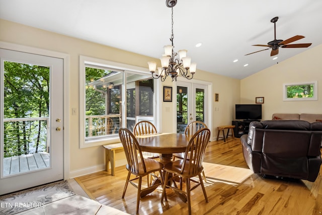 dining room featuring lofted ceiling, a chandelier, light wood-style flooring, baseboards, and ceiling fan