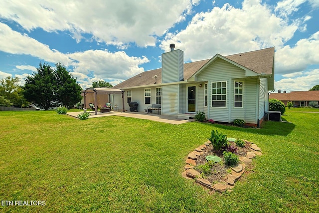 back of property featuring a patio, a chimney, a lawn, and roof with shingles
