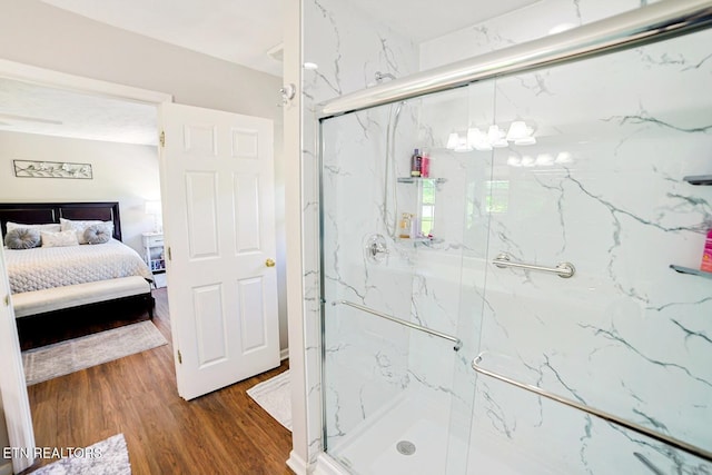 ensuite bathroom featuring a marble finish shower and wood finished floors