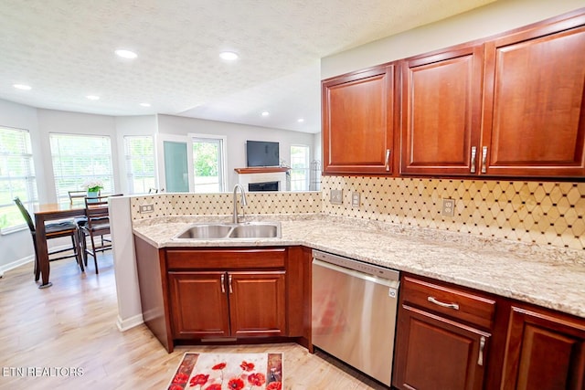 kitchen with dishwasher, a sink, light wood-style floors, a peninsula, and decorative backsplash