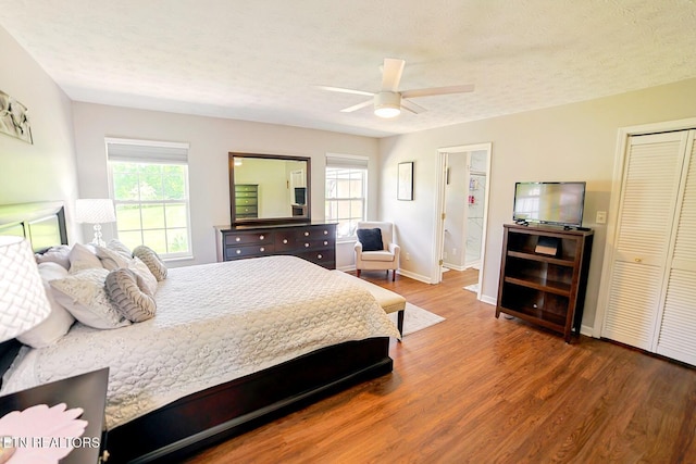 bedroom with multiple windows, wood finished floors, baseboards, and a ceiling fan