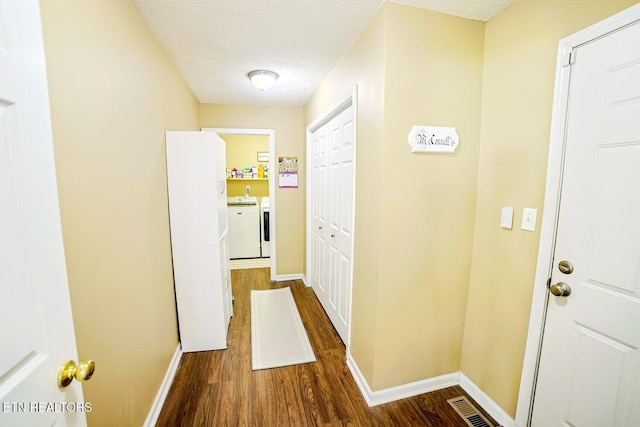 corridor featuring washer and clothes dryer, wood finished floors, and baseboards