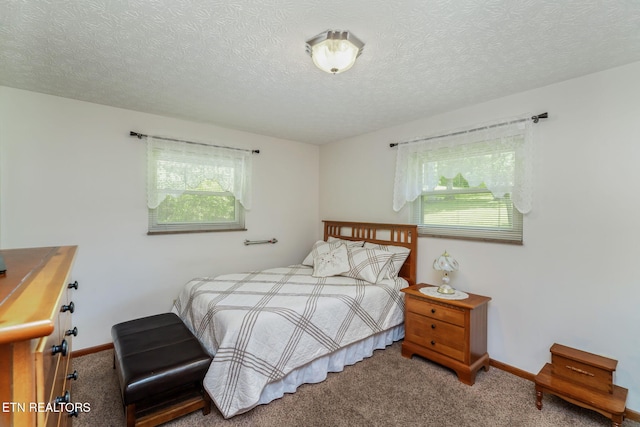carpeted bedroom featuring baseboards, multiple windows, and a textured ceiling