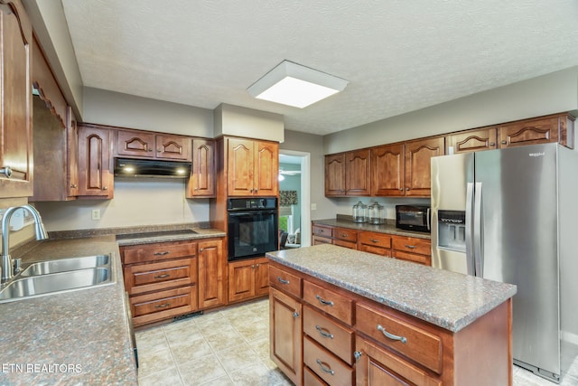 kitchen featuring under cabinet range hood, brown cabinets, a sink, and black appliances