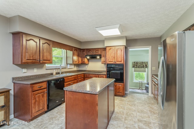 kitchen featuring dark countertops, a sink, a center island, under cabinet range hood, and black appliances