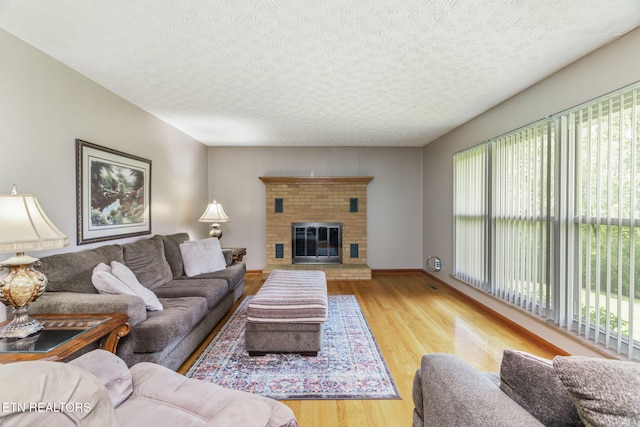 living area with a textured ceiling, wood finished floors, and a fireplace