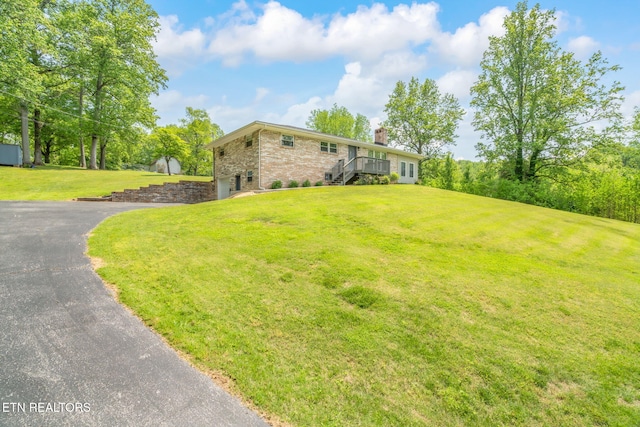 view of property exterior with a lawn, a garage, aphalt driveway, and a chimney