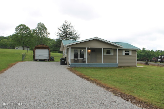 bungalow-style house with an outdoor structure, a front yard, metal roof, a porch, and driveway