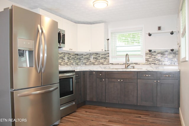 kitchen with tasteful backsplash, a sink, dark wood-style floors, stainless steel appliances, and white cabinetry