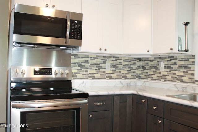 kitchen featuring appliances with stainless steel finishes, white cabinets, decorative backsplash, and dark brown cabinets