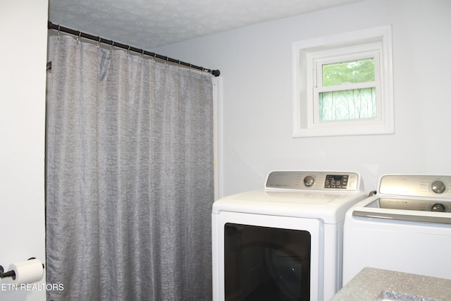 washroom with laundry area, a textured ceiling, and washer and clothes dryer