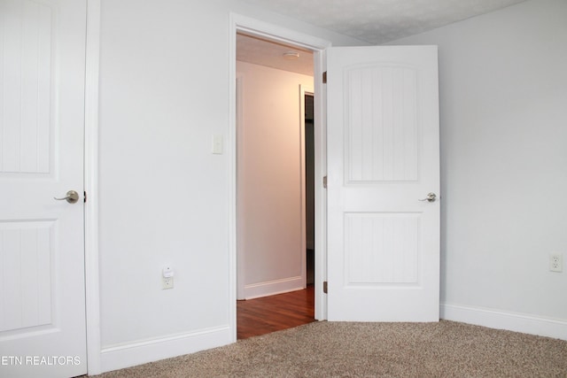 unfurnished bedroom featuring baseboards and dark colored carpet