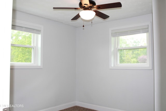 empty room featuring plenty of natural light, a ceiling fan, and baseboards