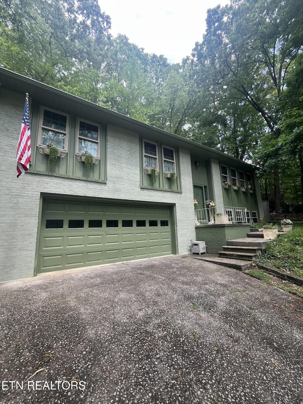 raised ranch featuring brick siding, driveway, and a garage