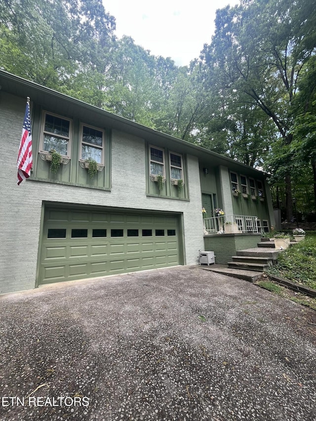 raised ranch featuring brick siding, driveway, and a garage