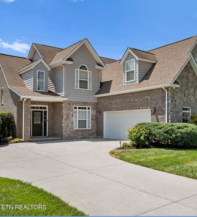 view of front of house with stone siding, driveway, and roof with shingles