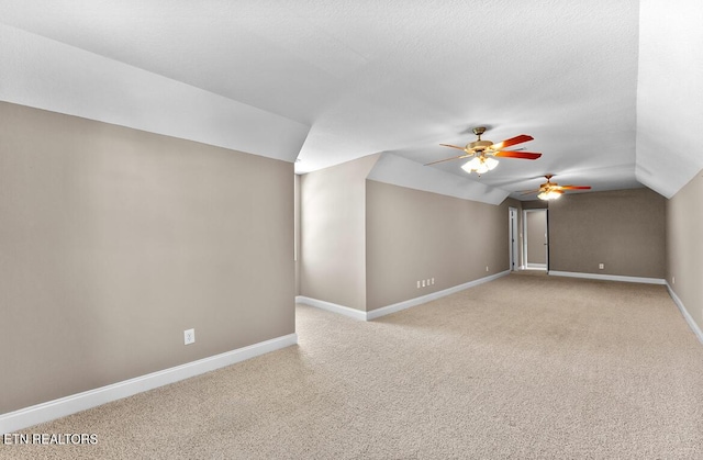 additional living space with baseboards, a ceiling fan, vaulted ceiling, and light carpet