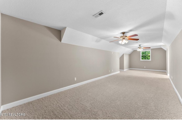additional living space featuring light carpet, a ceiling fan, baseboards, vaulted ceiling, and visible vents