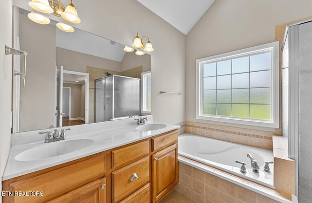 bathroom featuring double vanity, vaulted ceiling, a sink, and a stall shower