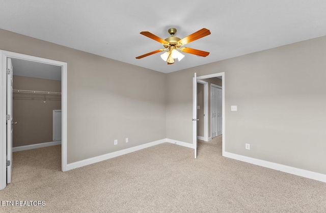 unfurnished bedroom with a spacious closet, baseboards, a closet, and light colored carpet